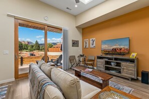 A living room with a sofa, coffee table, and TV stand, featuring a scenic outdoor view. - Rancho Rojo Casita - Kitchenette, Laundry, Views (Sedona)