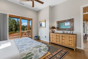 A bedroom with a bed, a dresser, a television, and a view of the outdoors. - Rojo Retreat - Main 2BR Unit, Hot Tub, Patio (Sedona)