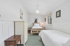 A bedroom with a bed, dresser, nightstand, and a painting on the wall. - Kalamunda Cottage (Kalamunda)