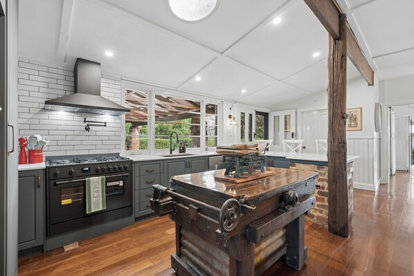 A spacious kitchen with modern appliances, a large island, and a rustic wood stove.