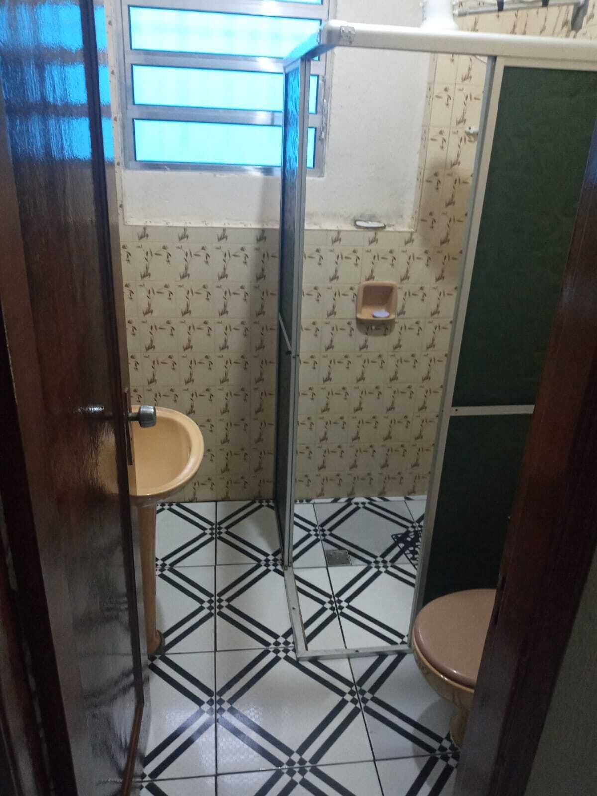 Pieni kylpyhuone, jossa on wc, pesuallas ja suihkukaappi.