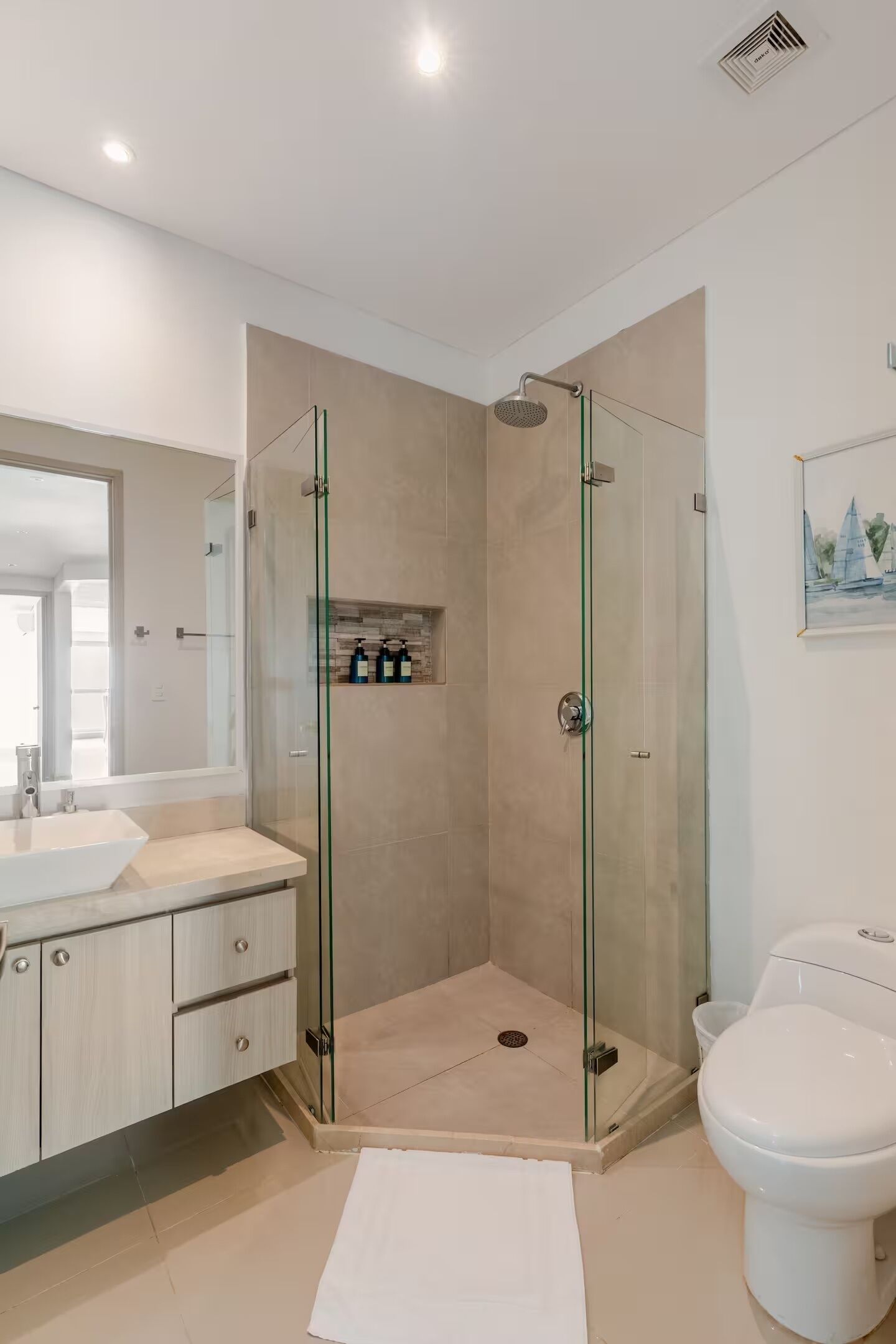 A modern bathroom with a glass-enclosed shower, a toilet, and a vanity with a mirror.