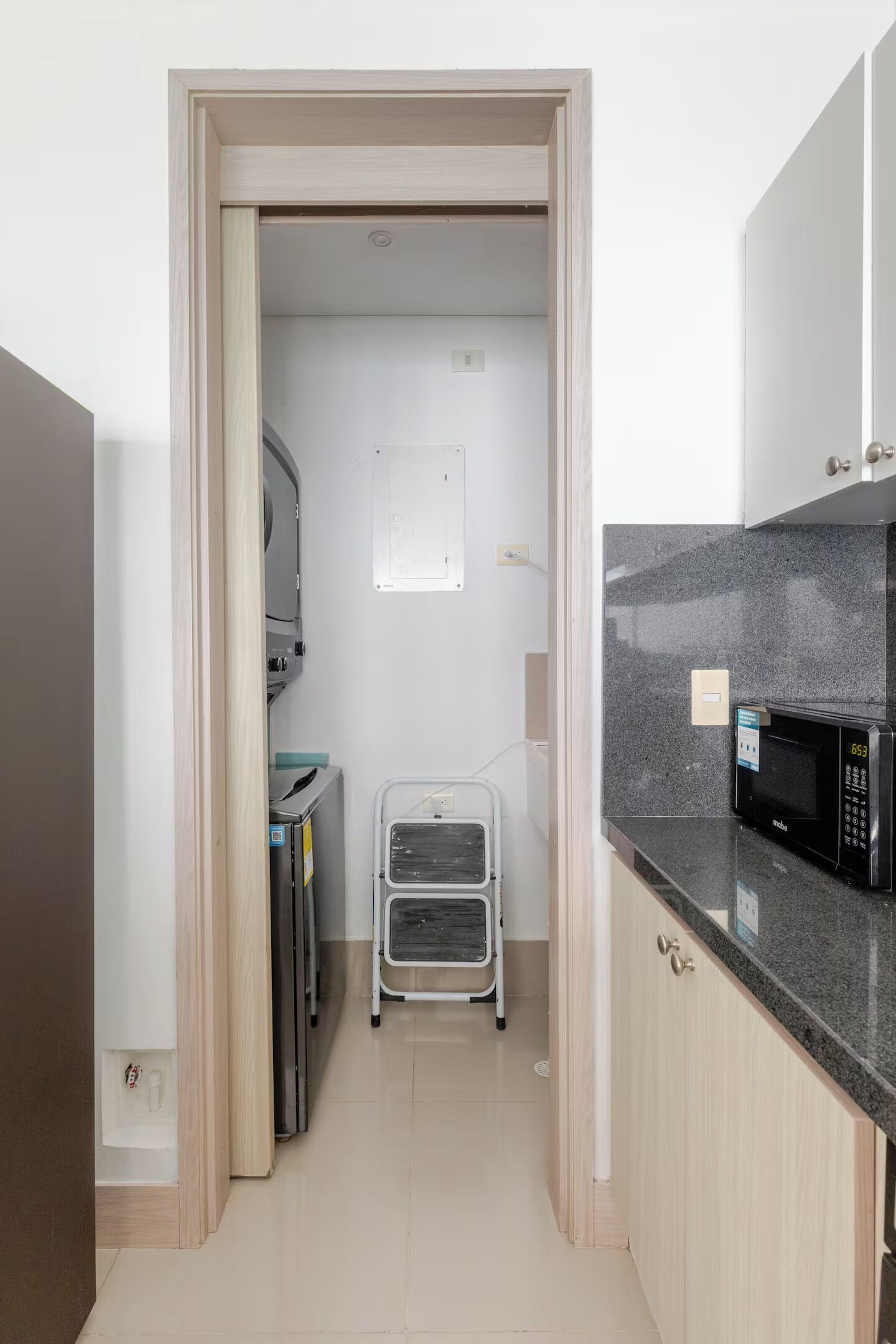 Una cocina pequeña y estrecha con microondas, armarios y un carrito.