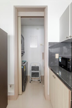 Una cocina pequeña y estrecha con microondas, armarios y un carrito.