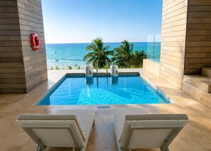Ein Swimmingpool mit Blick auf den Ozean, zwei Liegestühle und ein Rettungsring.