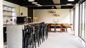 A modern bar area with a granite countertop, black bar stools, and pendant lighting.