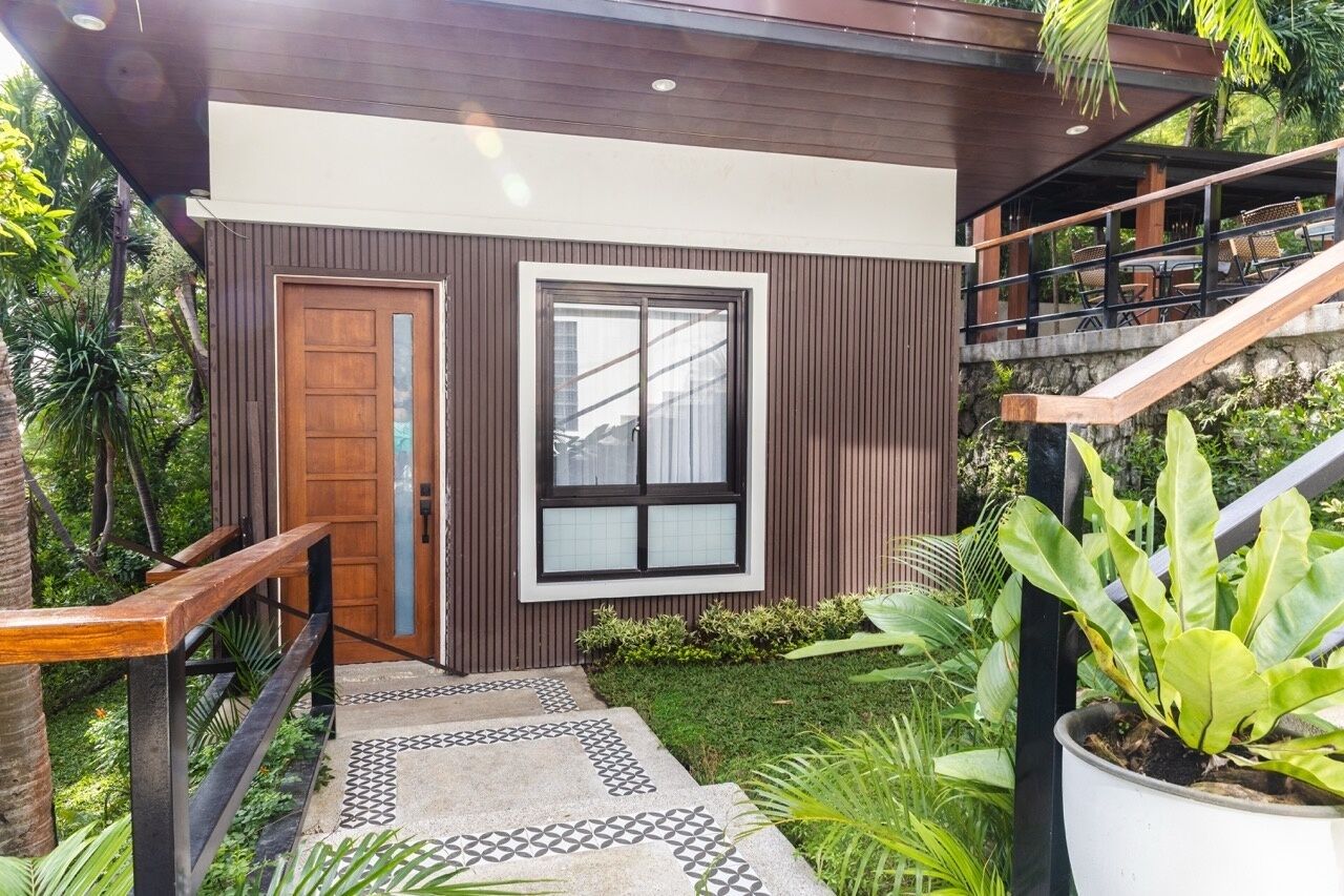 A modern building with a wooden door, a large window, and a staircase leading to an upper level.
