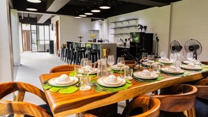 Ein Essbereich mit einem langen Tisch, der für eine Mahlzeit gedeckt ist, Stühlen und einer Küche im Hintergrund.