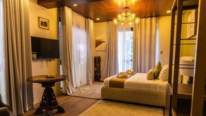 Ein Hotelzimmer mit Bett, Fernseher, einer Kristallleuchtre und Blick ins Freie.