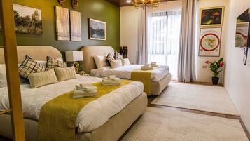A hotel room with two beds, a chandelier, artwork on the walls, and a potted plant.