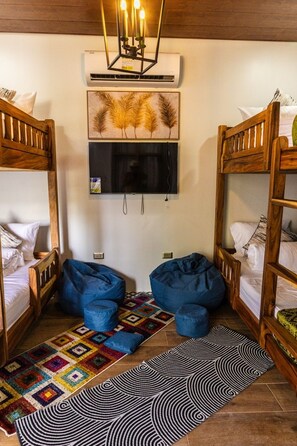 Una habitación con literas, un televisor montado en la pared y una alfombra estampada en el suelo.