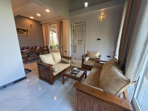A living room with a sofa set, a coffee table, and a dining area with chairs and a table. - Sunrise Villa (Nugaliyadda)