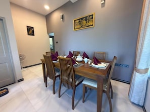 A dining area with a wooden table, four chairs, and purple napkins.