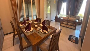 Un comedor con una mesa de madera dispuesta para cuatro, sillas y un sofá al fondo.