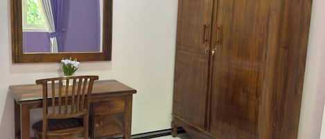 Una habitación con un escritorio de madera, una silla y un armario.