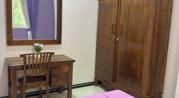 A room with a wooden desk, chair, and a wardrobe.