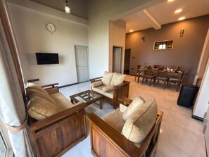 Amplia sala de estar con un conjunto de sofás, una mesa de centro y un televisor montado en la pared.