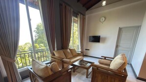Amplia sala de estar con un conjunto de sofás, una mesa de centro y un televisor montado en la pared.