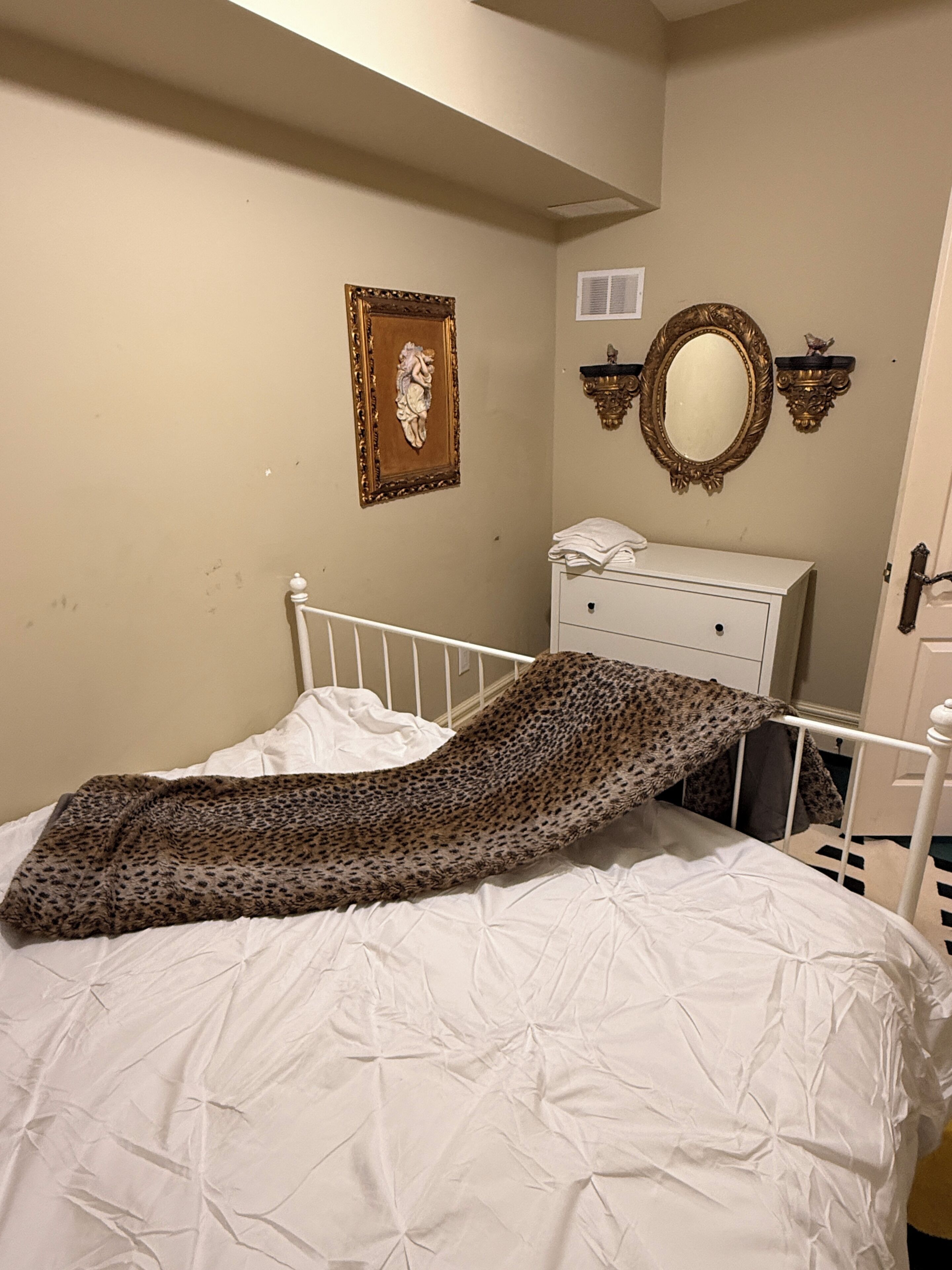 A bedroom with a bed, a dresser, a mirror, and a framed picture on the wall.