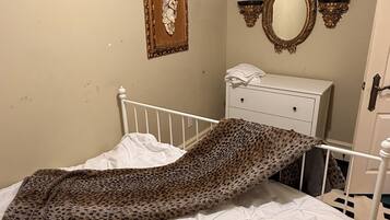 A bedroom with a bed, a dresser, a mirror, and a framed picture on the wall.