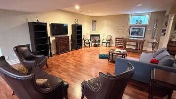 A living room with a fireplace, a flat-screen TV, leather chairs, a sofa, and a dining table.