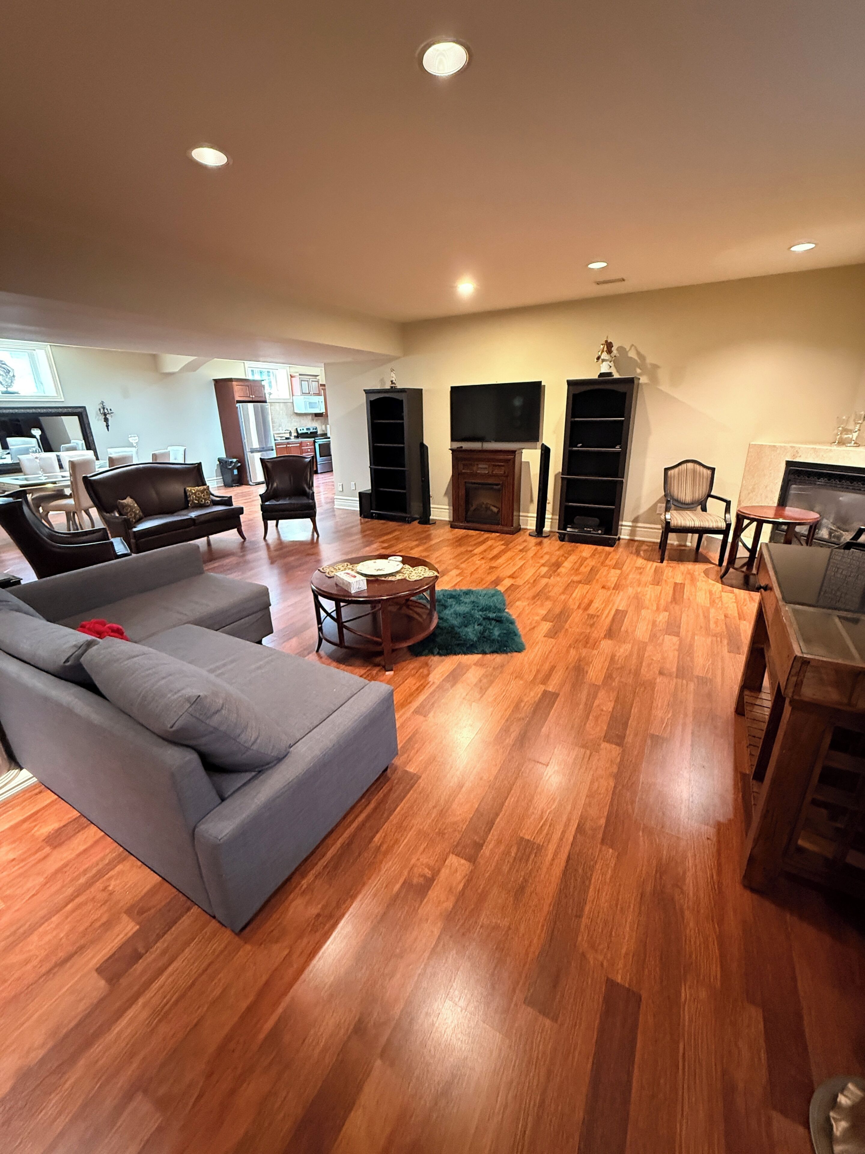 A spacious living room with hardwood flooring, a grey sofa, a coffee table, and a fireplace.
