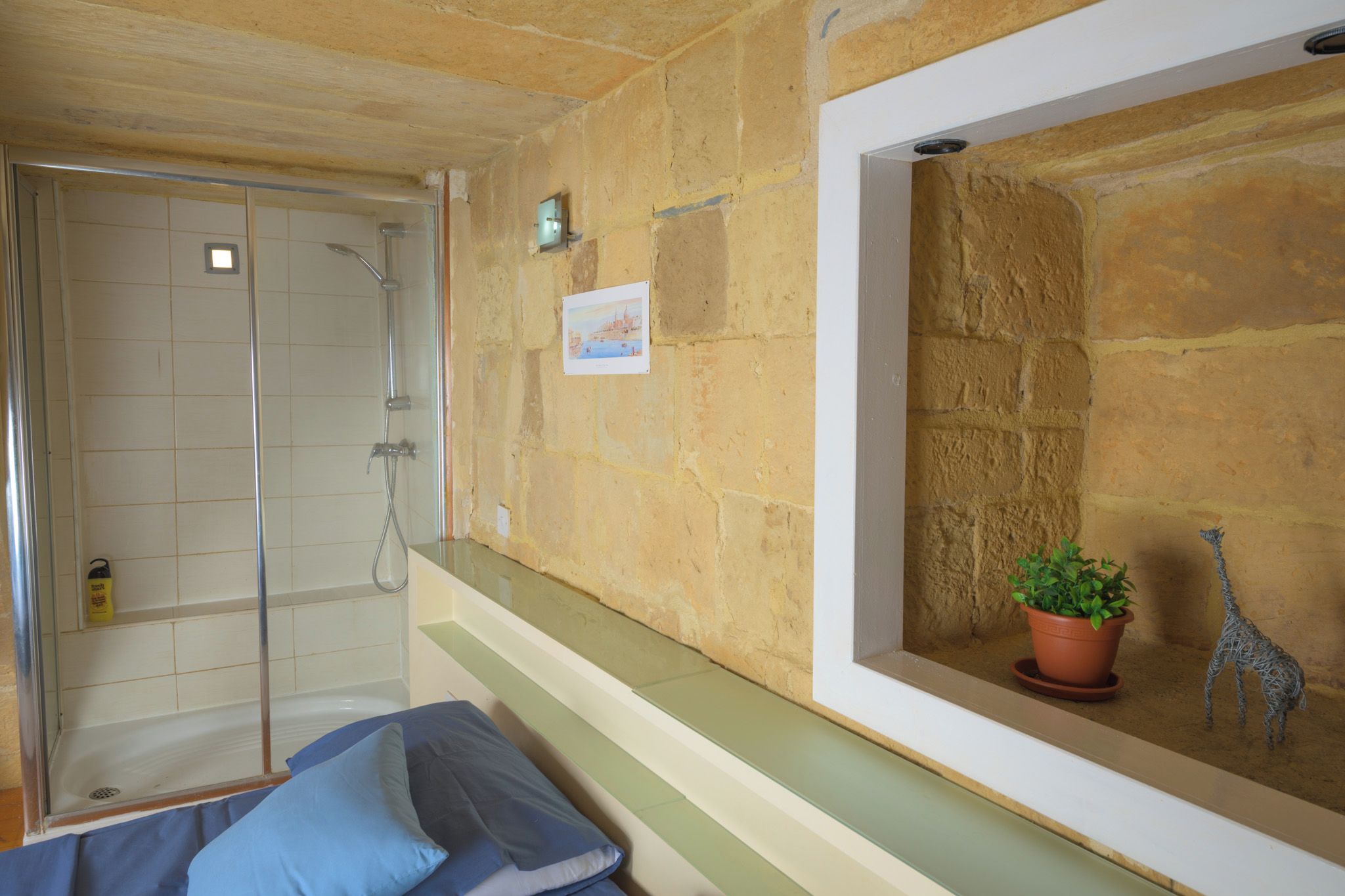 A bathroom with a shower, a potted plant, and a small giraffe decoration.