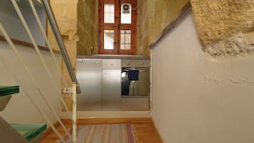 Una stretta scala conduce a una cucina con una porta in legno e una piccola finestra.