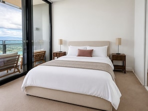 A hotel room with a large bed, two bedside tables, and a view through a glass door. - Vista in the Clouds - Coastal City Escape (Broadbeach)
