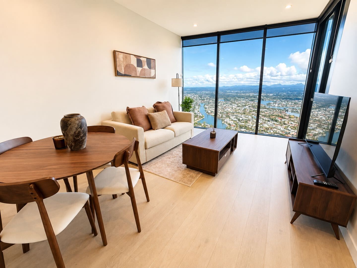 A modern living room with a dining area, a sofa, a coffee table, and a TV on a stand.