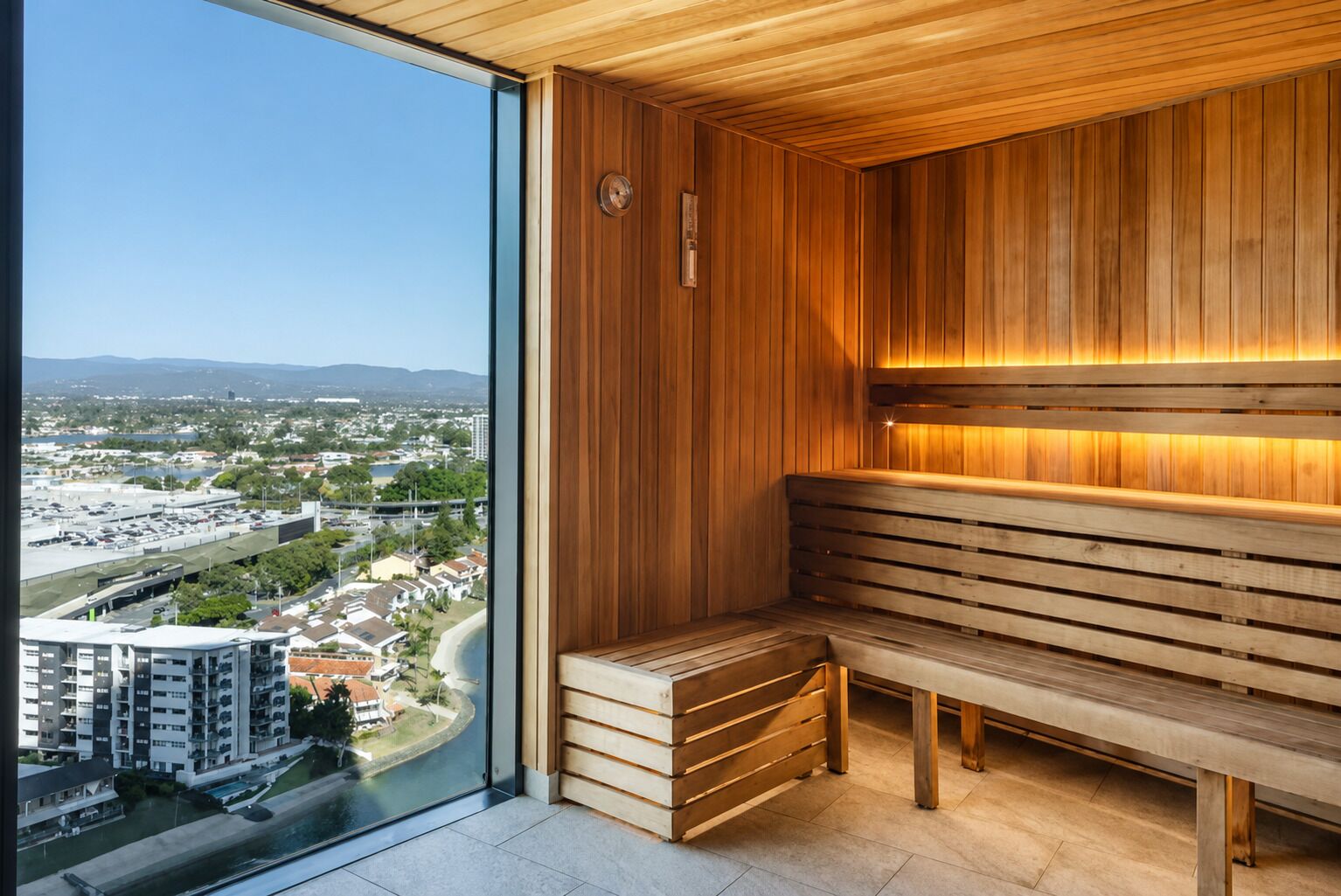 A sauna with wooden benches and a view of a cityscape through a large window.