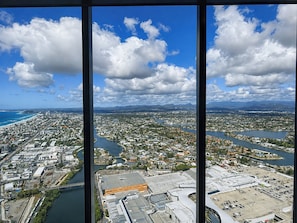 A panoramic view of a coastal city with a river, industrial buildings, and residential areas. - Vista in the Clouds - Coastal City Escape (Broadbeach)