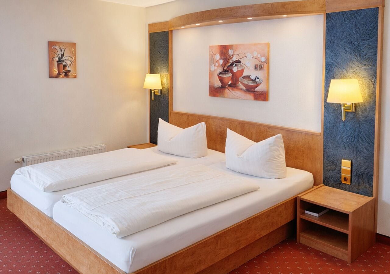 Ein Hotelzimmer mit einem Doppelbett, zwei Nachttischen und Wandlampen.