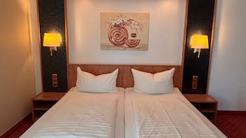 Una cama doble con cabecera de madera, dos mesitas de noche con lámparas y una obra de arte colgada en la pared.