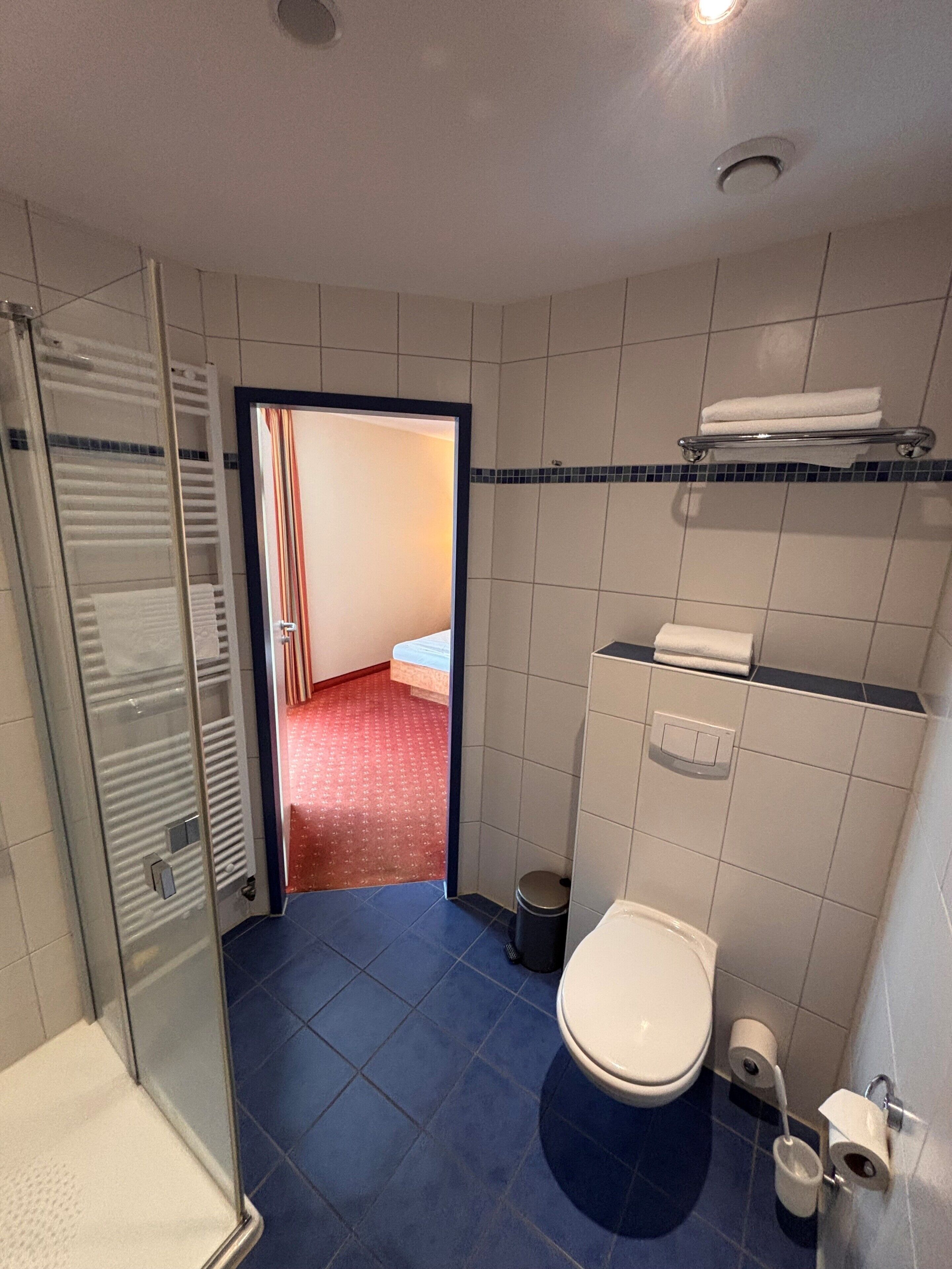 Une salle de bain d’hôtel équipée d’une douche, de toilettes et d’un porte-serviettes.