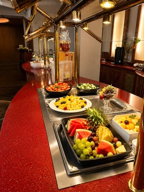 A buffet setup with various fruits and vegetables arranged on a red countertop. - Landgasthof Alte Post  (Aurich)