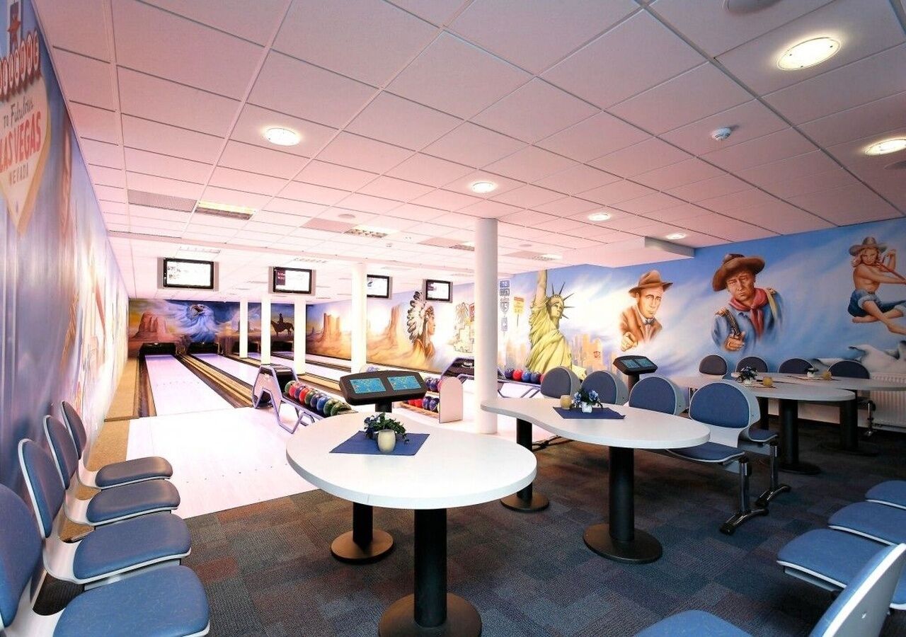 A bowling alley with multiple lanes, seating areas, and a mural of a cowboy on the wall.