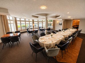 A conference room with round tables, chairs, and a large window providing a view of the outdoors. - Landgasthof Alte Post  (Aurich)