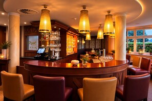 A bar area with a curved counter, multiple seating options, and pendant lighting.