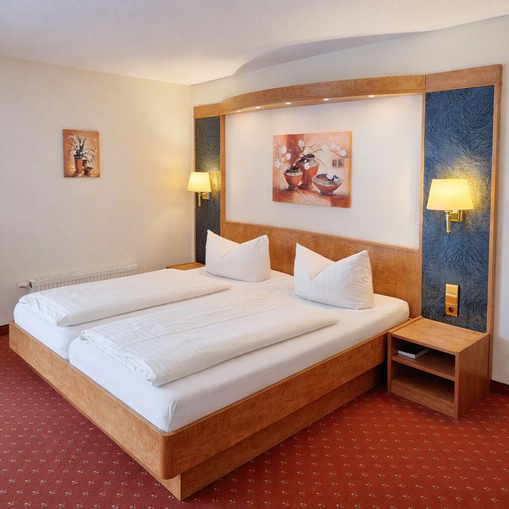 Una cama doble con dos almohadas, una mesita de noche con lámpara y una obra de arte colgada en la pared.