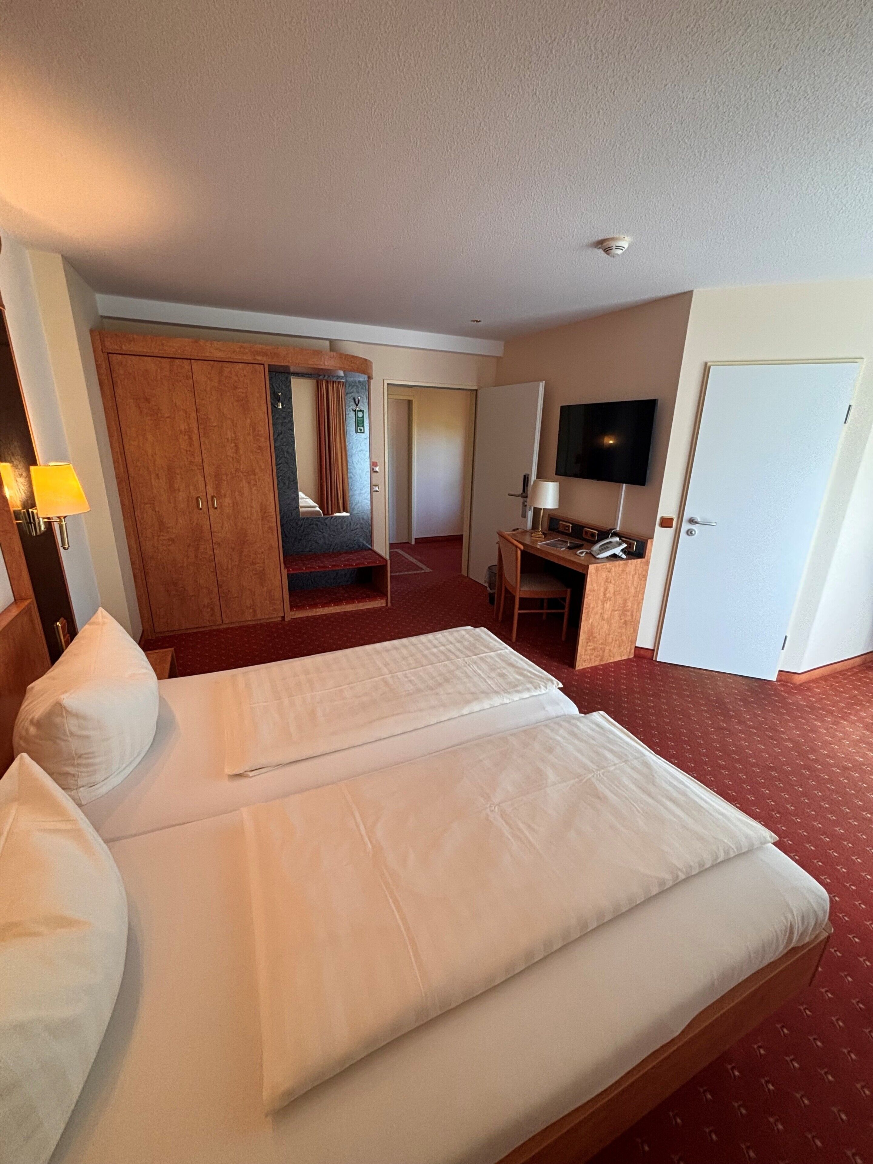 Una habitación de hotel con una cama grande, un escritorio, un televisor y un armario.