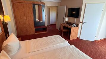 Una habitación de hotel con una cama grande, un escritorio, un televisor y un armario.