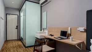 Una habitación de hotel con escritorio, silla, computadora portátil, mesita de noche y cama.