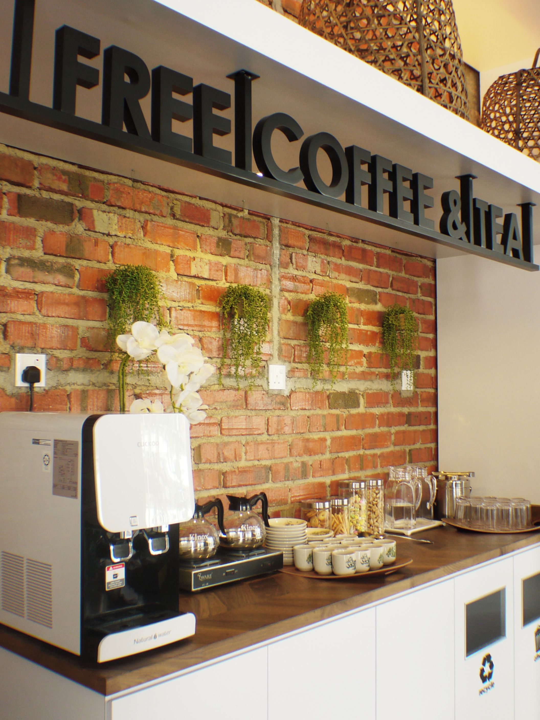 A coffee station with a coffee machine, tea kettle, and various mugs and cups.