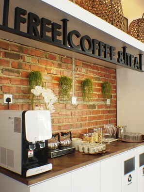 A coffee station with a coffee machine, tea kettle, and various mugs and cups.