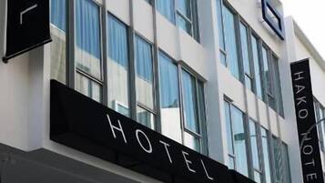 A modern hotel building with a prominent sign reading 'HAKO HOTEL' and a logo below.