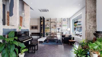 A modern living room with a piano, seating area, and a large window with a view of the street.