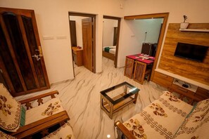 Una sala de estar con sofá, una mesa de centro, un televisor montado en la pared y un aparador de madera.
