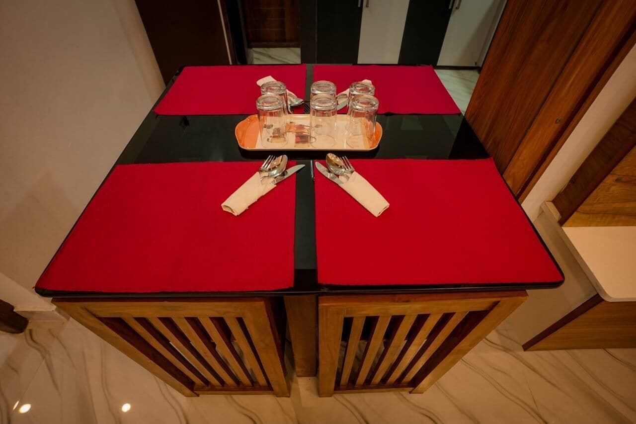A dining table with red tablecloths, a tray with glassware, and wooden chairs.