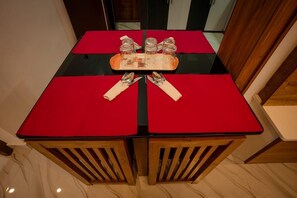 Una mesa de comedor con manteles rojos, una bandeja con cristalería y sillas de madera.